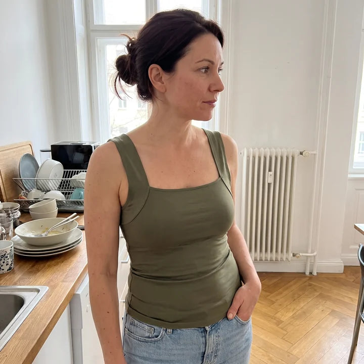 Femme dans sa cuisine en débardeur à soutien-gorge intégré vert olive et jean